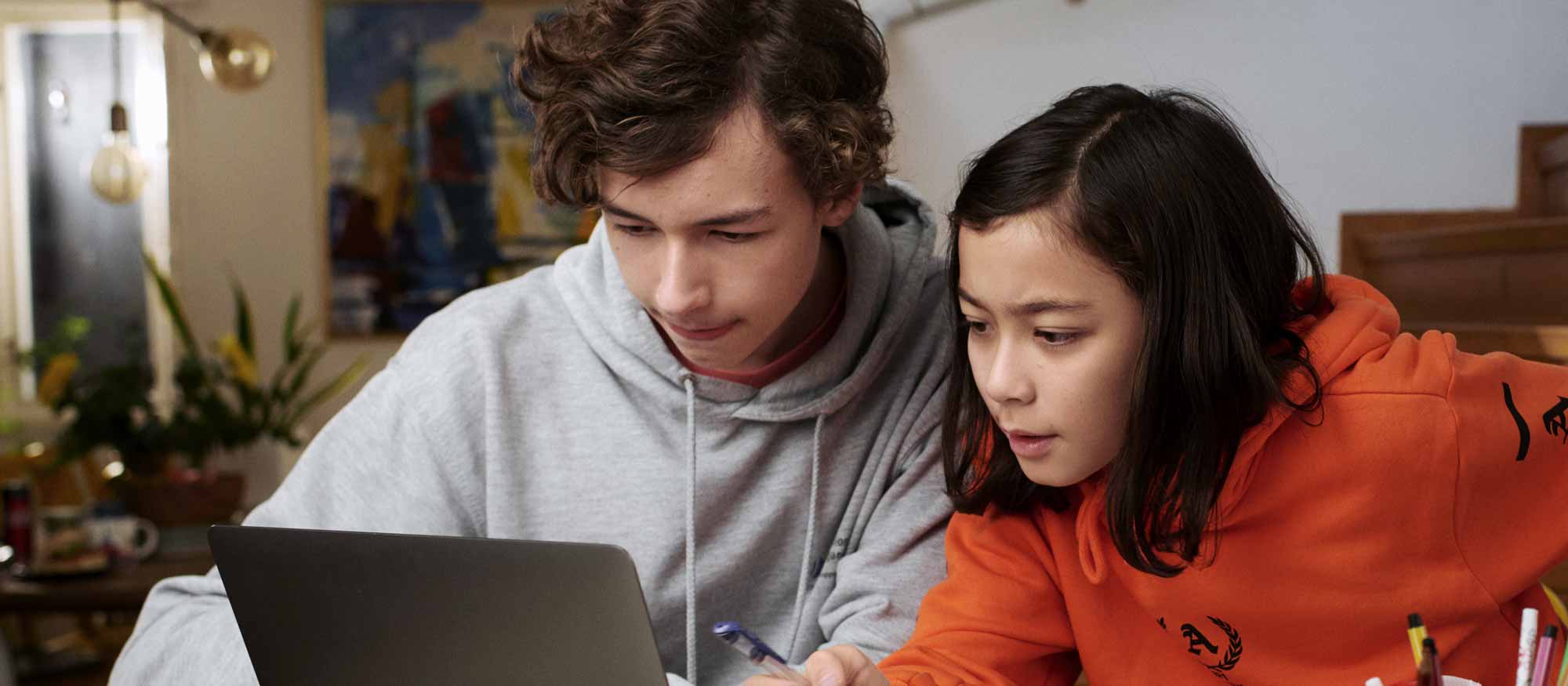 Två tonåringar gör läxor på en dator i hemmet